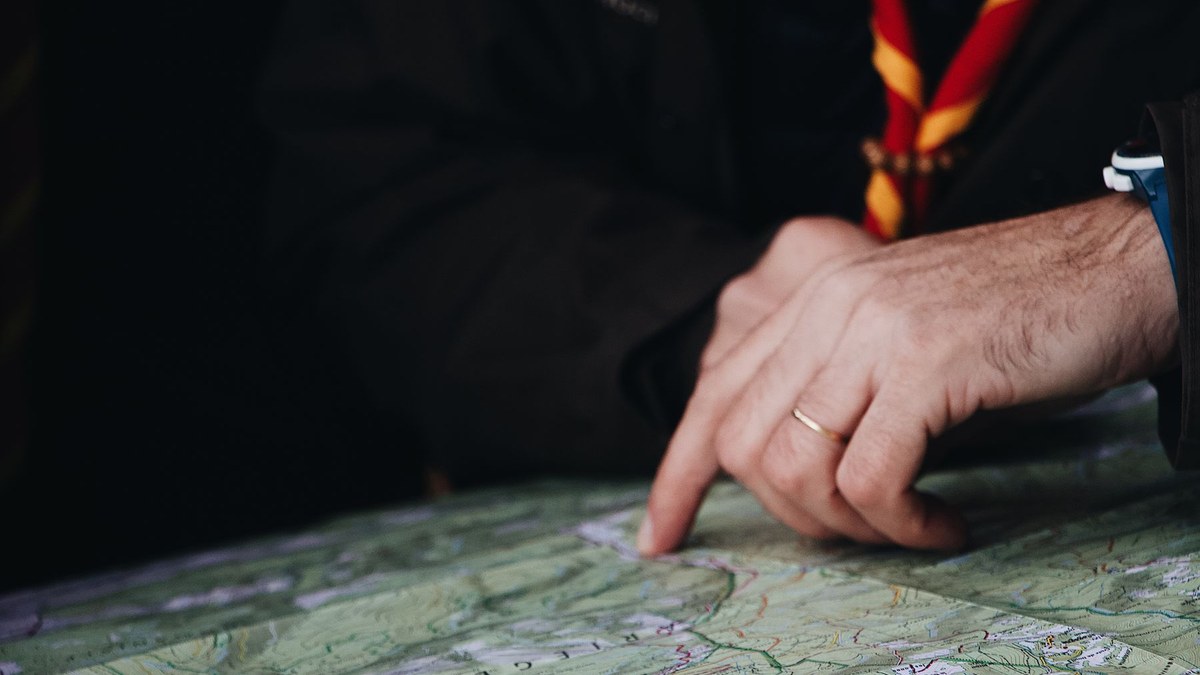 Homem apontando em mapa para comparar localização, rotas e moradia.