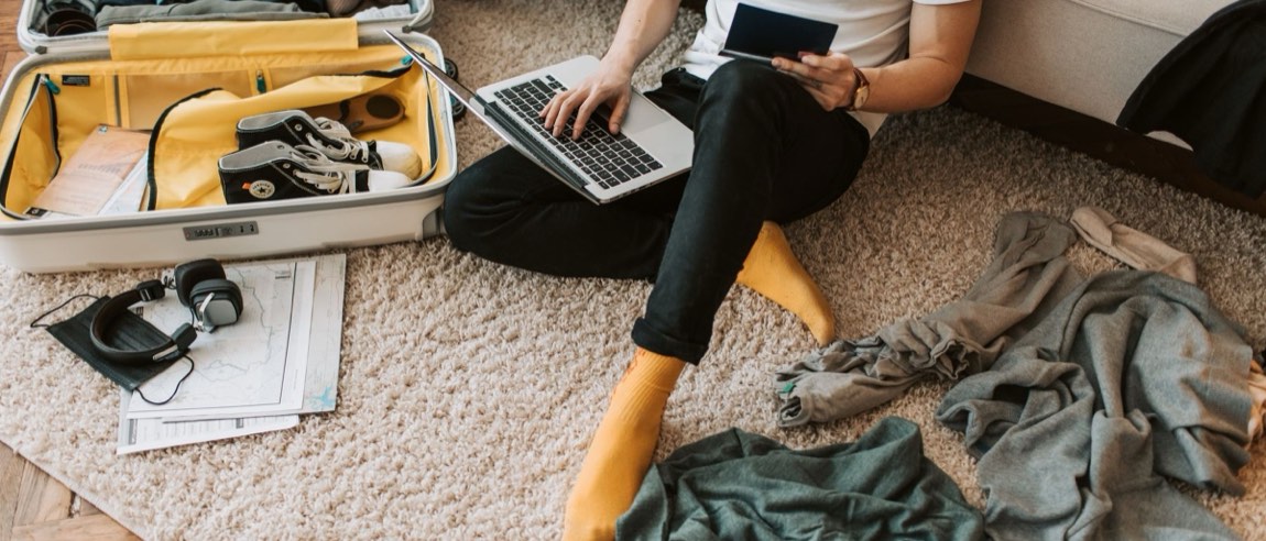 Pessoa organizando notebook, celular e mala na primeira semana de chegada a Brasília.