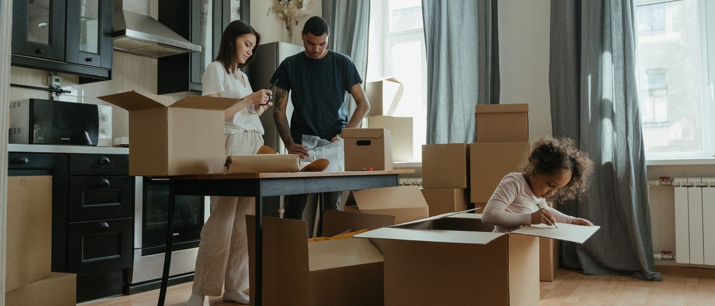 Família desempacotando caixas em apartamento novo durante a organização de uma mudança para Brasília.